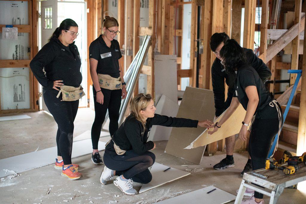 Love, Corbin team at the Habitat for Humanity build 2022: featuring 5 people measuring drywall