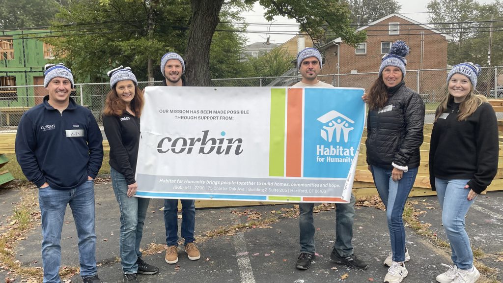 Love, Corbin team at the Habitat for Humanity build 2023: the team holding a banner with the Corbin and Habitat for Humanity logos